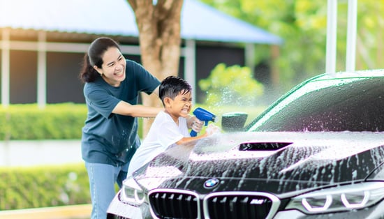 BMW M1の親子が仲良く洗車している後ろ姿。水がかかり、楽しそうに涼しげな雰囲気が漂う瞬間を捉えた写真。