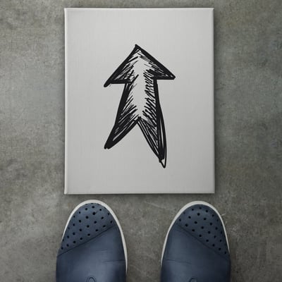 Hand drawn arrow design doodle icon on front of business man feet as concept