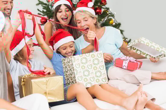 Happy family at christmas opening gifts together on the couch