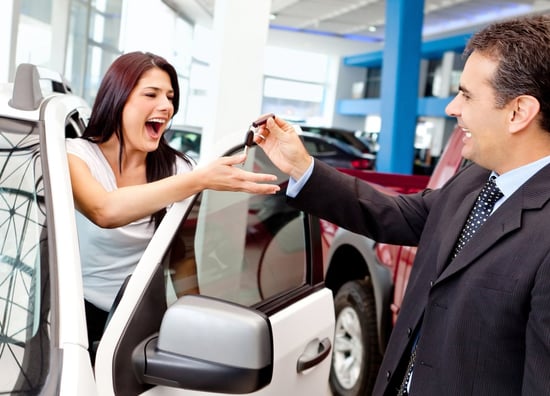 Happy woman buying a new car and salesman handling keys