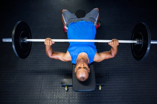 High angle view of man doing bench press with barbell in fitness studio