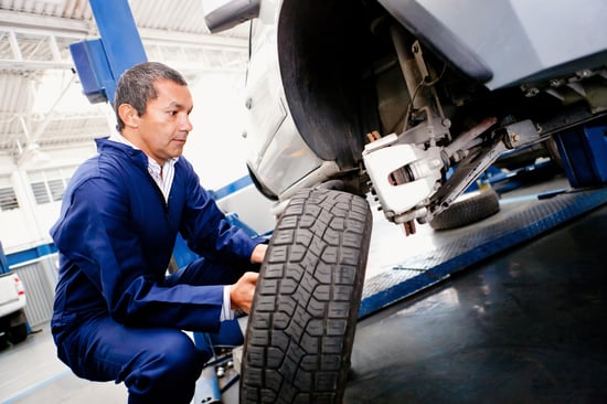Mechanic placing a wheel back into a car