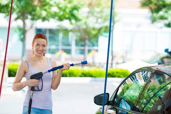 Picture, portrait young, smiling, happy, attractive woman washing automobile at manual car washing self service station, cleaning with foam, pressured water. Transportation, auto, vehicle care concept